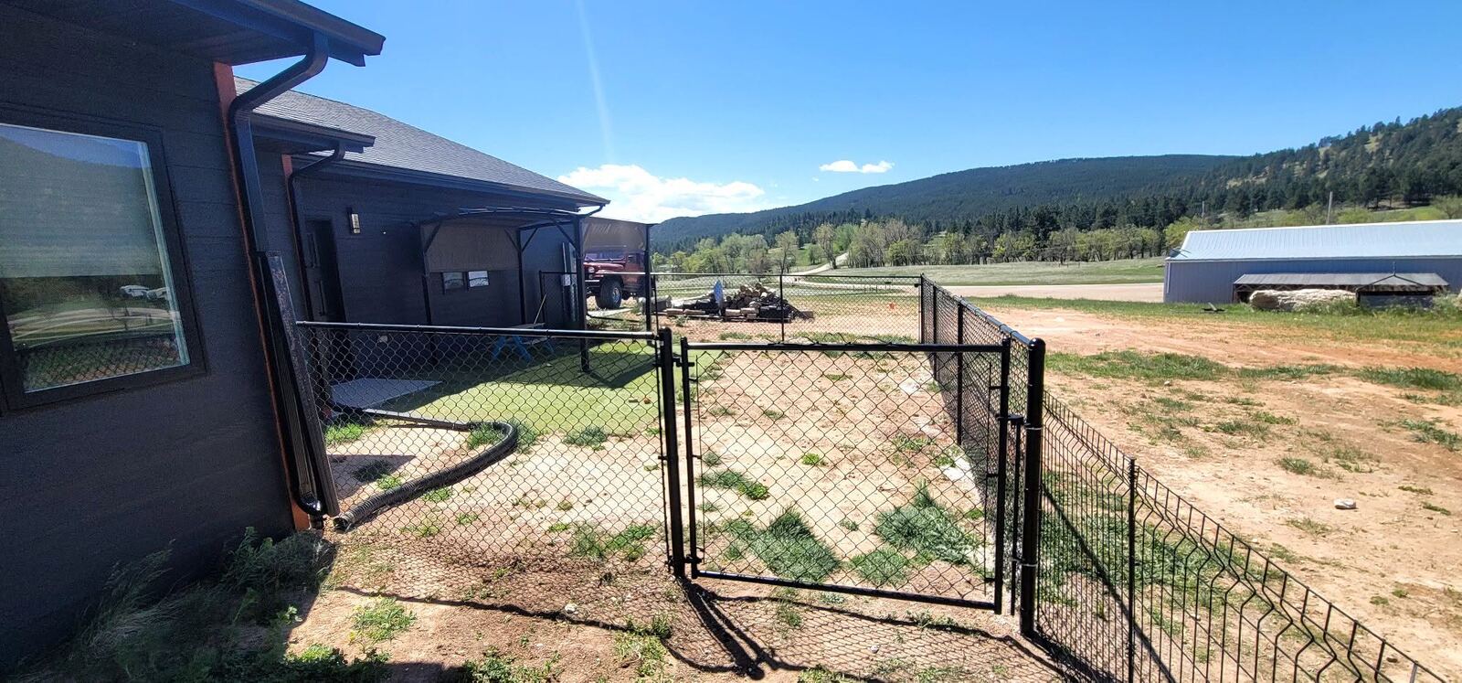 Exterior gutter and downspout work alongside a new fence and gate